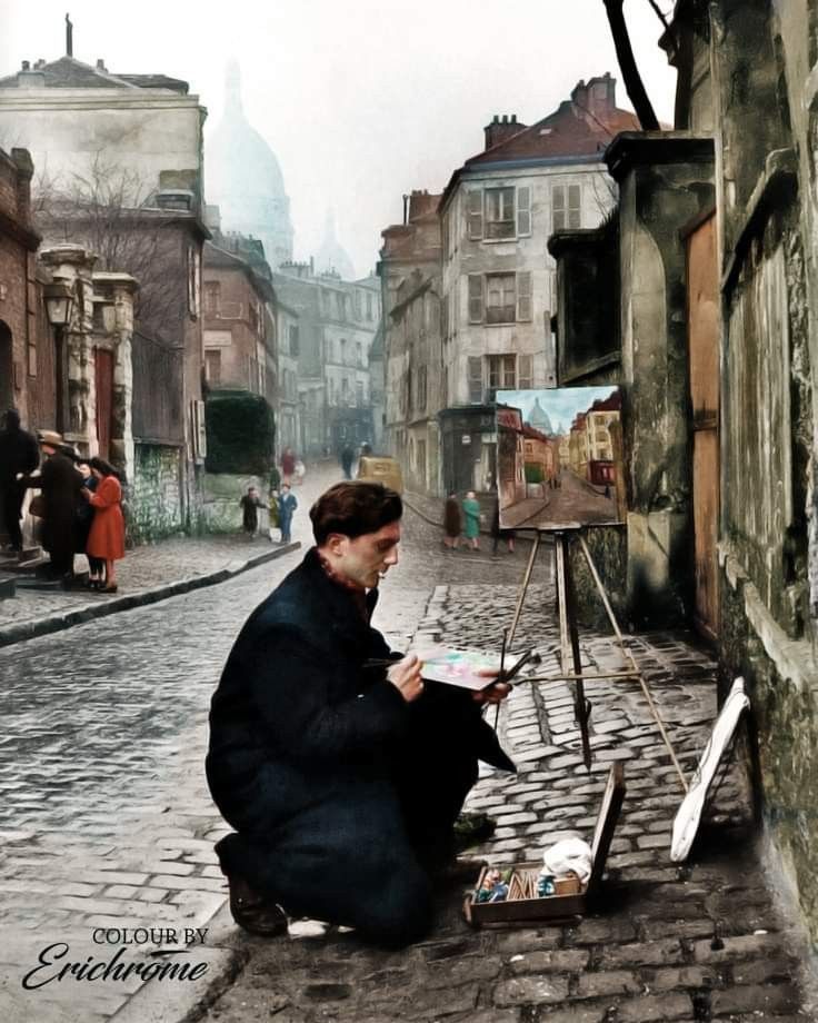 a man is sitting on the street painting