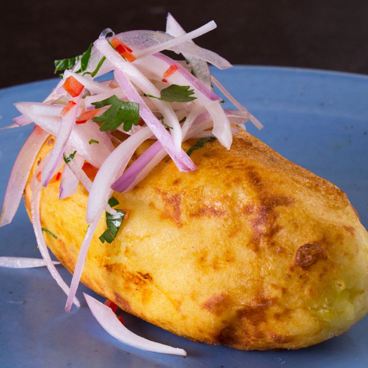 a blue plate topped with an omelet covered in onions and cilantro