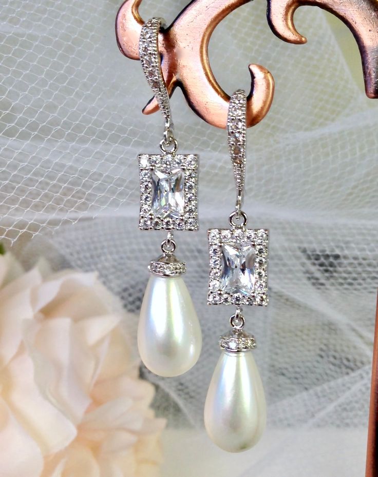 Elegant. Classic. Perfect. Featuring 15mm teardrop shell pearls (natural), this elegant pair of earrings will add glamour to any wedding dress or formal ensemble. All it takes is a simple glance at this unique design to see its extremely classy look that makes an elegant and feminine statement. Shining brightly and quite eye-catching, the shimmer of the pearls is given an extra boost by the clear cubic zirconia that adorn them. Length: 2" (approx. 5cm); Width: 0.4" (approx. 1cm); Weight: 6g. Ava Silver Pearl Drop Clip-on Earrings For Evening, White Pearl Drop Clip-on Earrings For Wedding, Pear-shaped Bridal Earrings For Evening, Elegant Silver Clip-on Earrings With Pearl Drop, Elegant Pear-shaped Earrings For Formal Occasions, Pear-shaped White Bridal Earrings For Wedding, Elegant Silver Pearl Earrings, Elegant Pearl Drop Earrings For Wedding, Formal White Teardrop Pendant Earrings