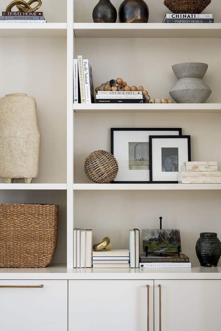 a white bookcase with books and vases on it's shelves in a living room