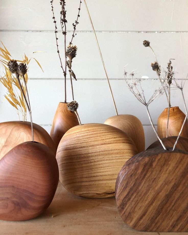 four wooden vases with dried plants in them