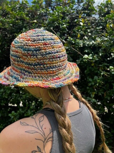 a woman wearing a multicolored hat with braids and tattoos on her arm