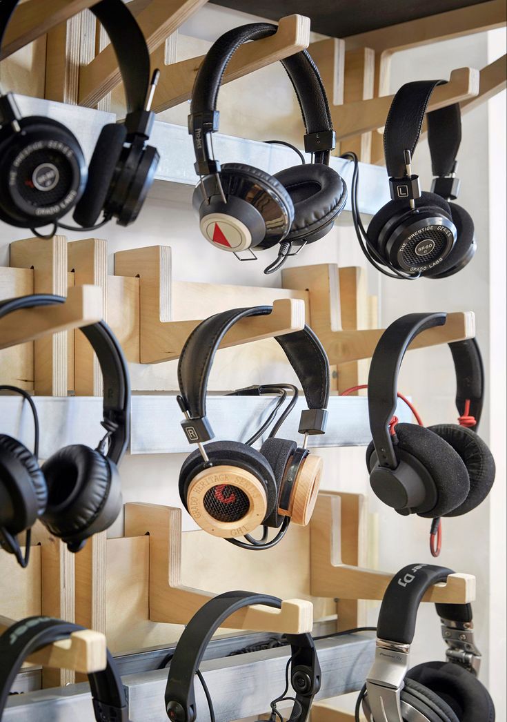 headphones are hanging up on the wall in front of wooden racks with ear phones