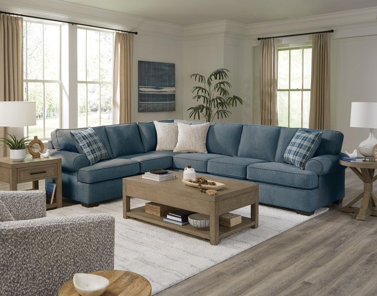 a living room with blue couches and white rugs on the hardwood flooring