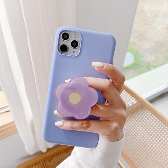 a woman holding up her phone case with a purple flower on the front and side