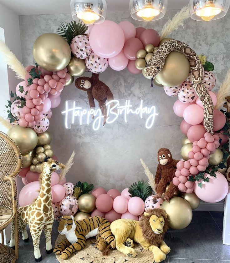 a birthday decoration with balloons and animals on the floor next to a wall that says happy birthday