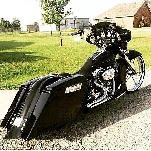 a black motorcycle parked on the side of a road next to a grass covered field