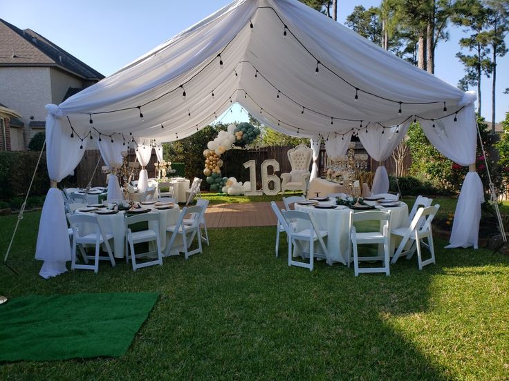 a white tent set up with tables and chairs for an outdoor wedding reception in the backyard