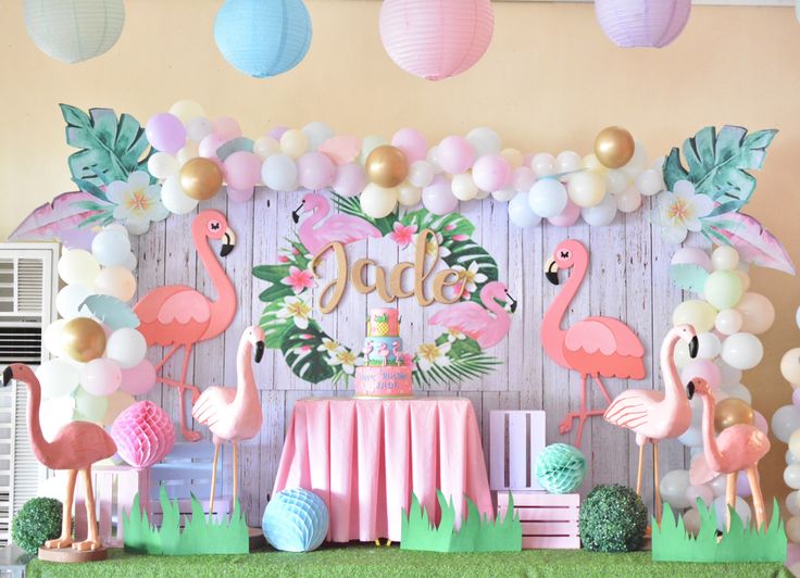 a birthday party with flamingos and balloons on the wall, table cloths and decorations