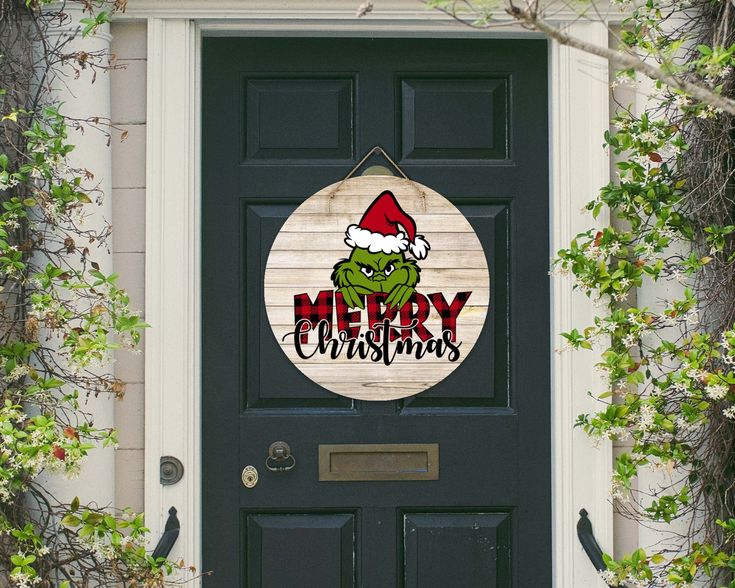 a door with a merry christmas sign hanging on it's side and green plants growing around