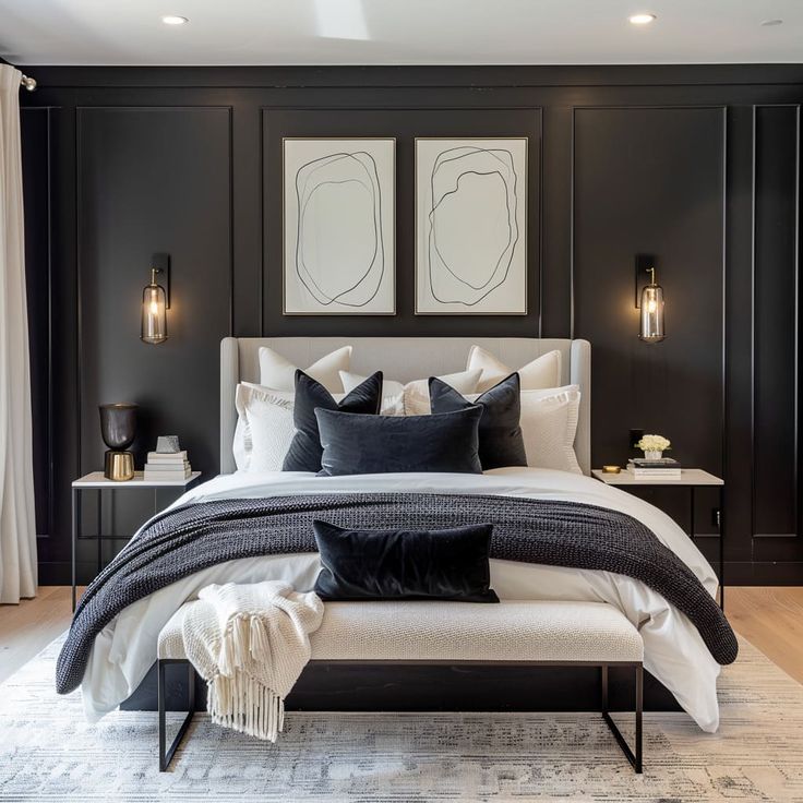 a bedroom with black walls and white bedding, two framed pictures on the wall