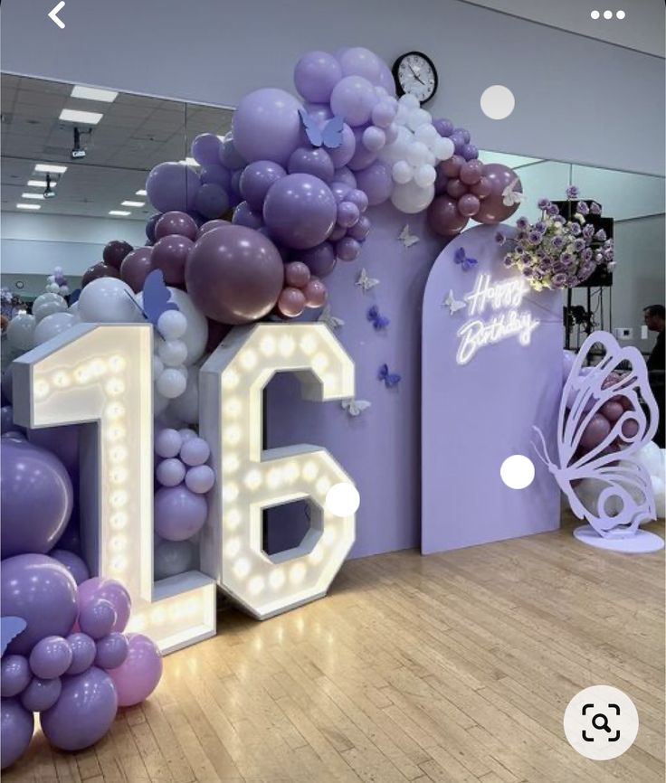 the number sixteen is displayed in front of balloons and flowers on display at an event