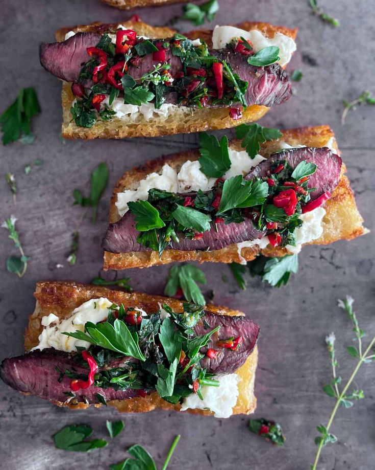 four pieces of bread with meat and vegetables on them sitting on top of a table