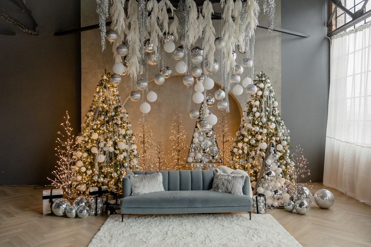 a living room decorated for christmas with silver and white decorations on the walls, couches, and trees