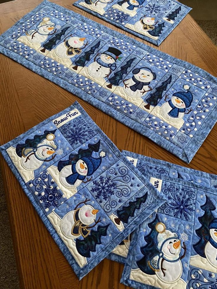 quilted placemats with snowmen on them sitting on top of a wooden table