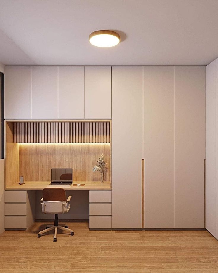 an office with white walls and wooden flooring is lit by a round light above the desk