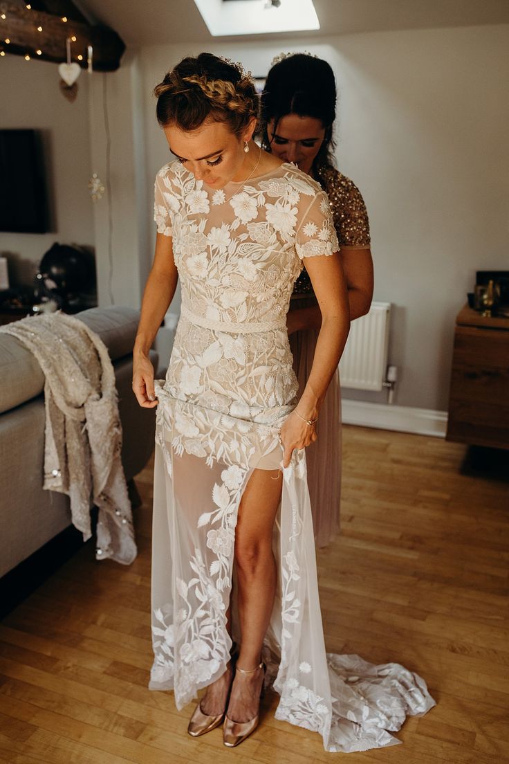 two women standing in a room with one woman wearing a dress and the other looking down