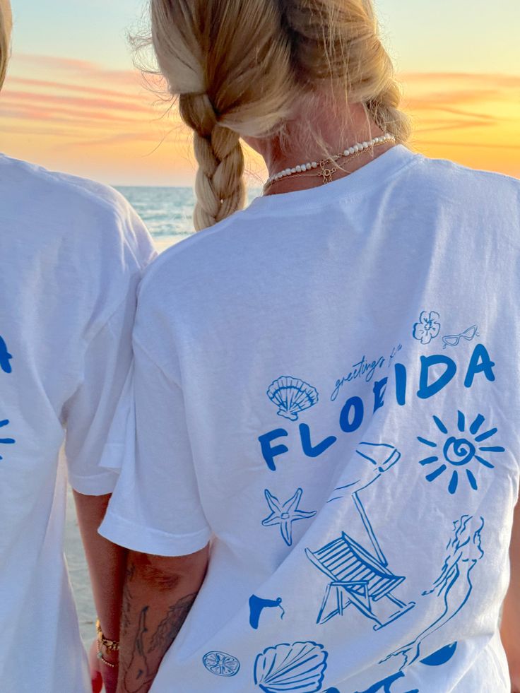 Our EXCLUSIVE Greetings From Florida Sunhoney T-shirt is perfect for beach lovers! This Comfort Colors t-shirt features a playful blue drawn design of popular Florida symbols like the sun, shell, mermaid, and more. Style this shirt over your fave bikini as your new go-to beach tee or style with biker shorts and sneakers for the cutest summer fit! Designed by us, handmade by us in Jacksonville Beach, FL Product is made to order: available for pick up/ships in 2-4 business days Content: 100% Cotto Graphic Tee T-shirt For Family Vacation, Blue Cotton T-shirt For Family Vacation, Blue Crew Neck Top For Family Vacation, Blue Cotton Tops For Family Vacation, Blue Graphic Print T-shirt For Family Vacation, Beach Season Tops With Screen Print For Summer Adventures, Summer Blue T-shirt With Screen Print, Summer Blue T-shirt For Vacation, Blue Crew Neck T-shirt For Vacation