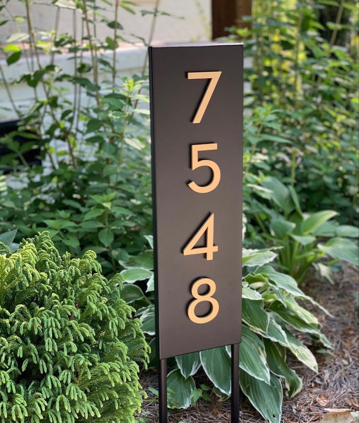 an address sign stands in front of some plants