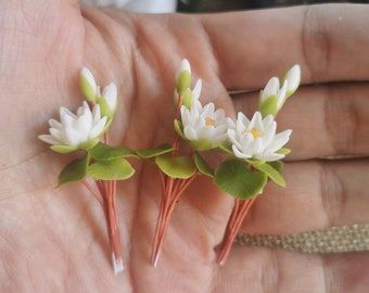 three small white flowers sitting on top of each other in someone's hand,