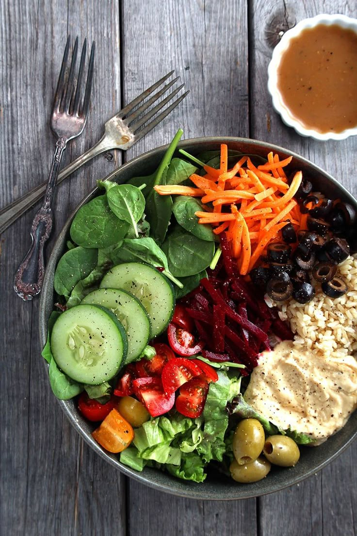 a bowl filled with different types of food next to a fork and knife on top of a wooden table