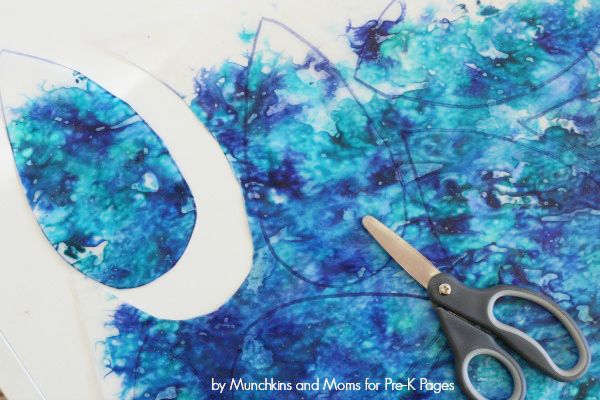 scissors sitting on top of a piece of paper next to blue and white art work