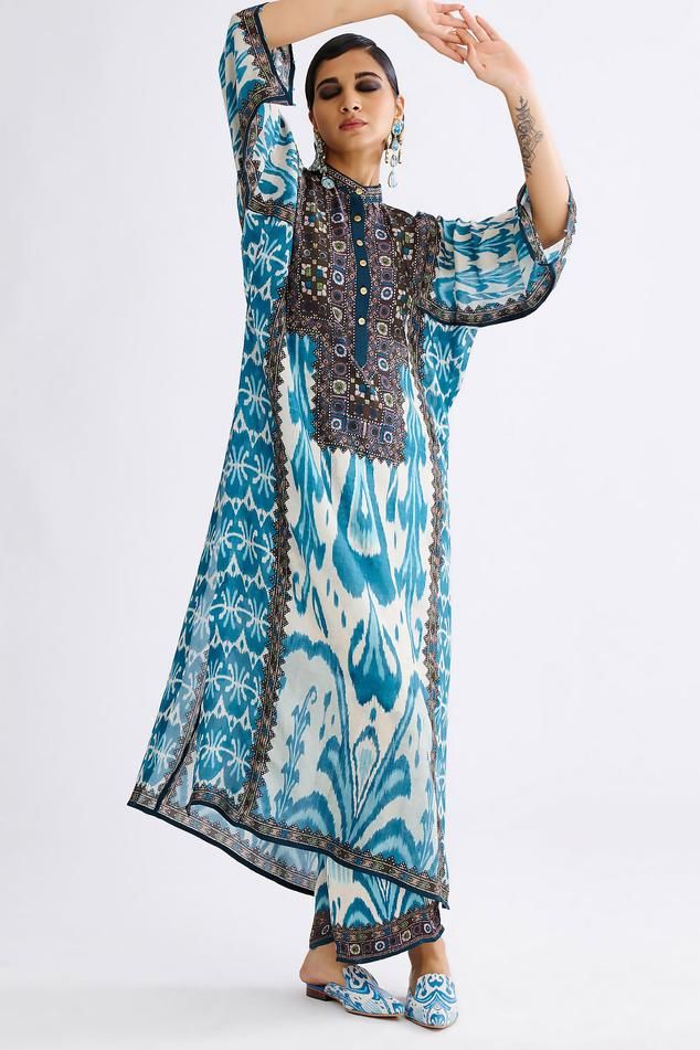 Aqua tunic with floral, geometric print and band collared neckline.
Components: 1
Pattern: Printed
Type Of Work: Floral, geometric
Neckline: Band collar
Sleeve Type: Three quarter
Fabric: Silk
Color: Blue
Other Details: 
Front button detailing
Note: Pant, earrings worn by the model is not for sale
Occasion: Puja - Aza Fashions Bohemian Printed Tunic For Eid, Blue Straight Kurta Tunic For Spring, Silk Bohemian Tunic With Floral Print, Bohemian Silk Tunic With Floral Print, Blue Long Sleeve Kaftan With Floral Print, Bohemian Floral Print Tunic For Eid, Blue Floral Print Long Sleeve Kaftan, Bohemian Eid Tunic With Printed Motifs, Blue Boho Print Kaftan For Spring