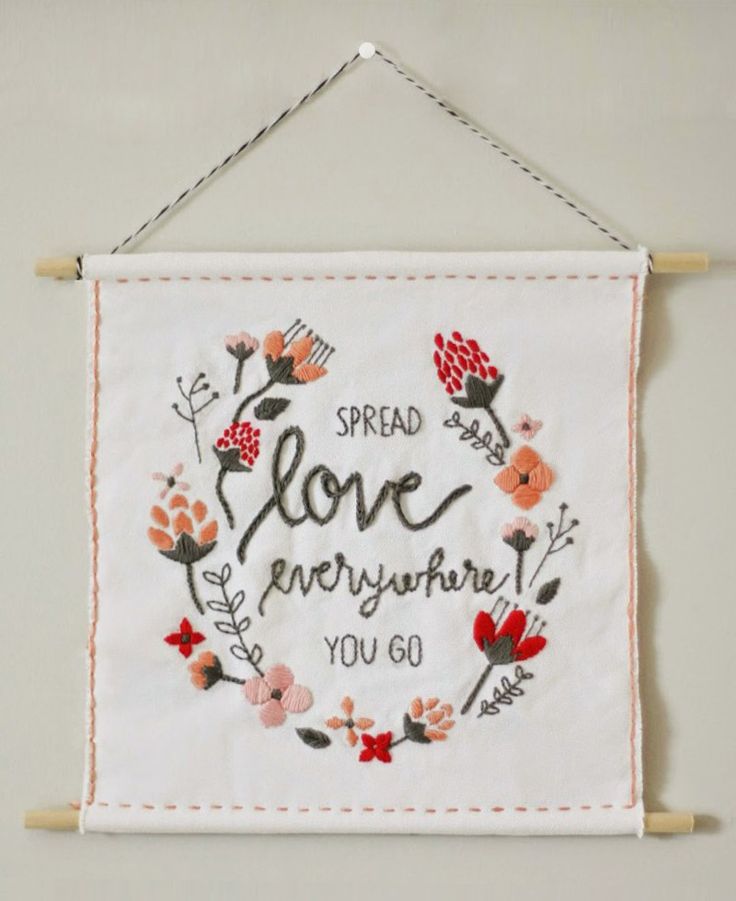 a cross - stitch sign hanging on a wall that says, spread love everywhere you go