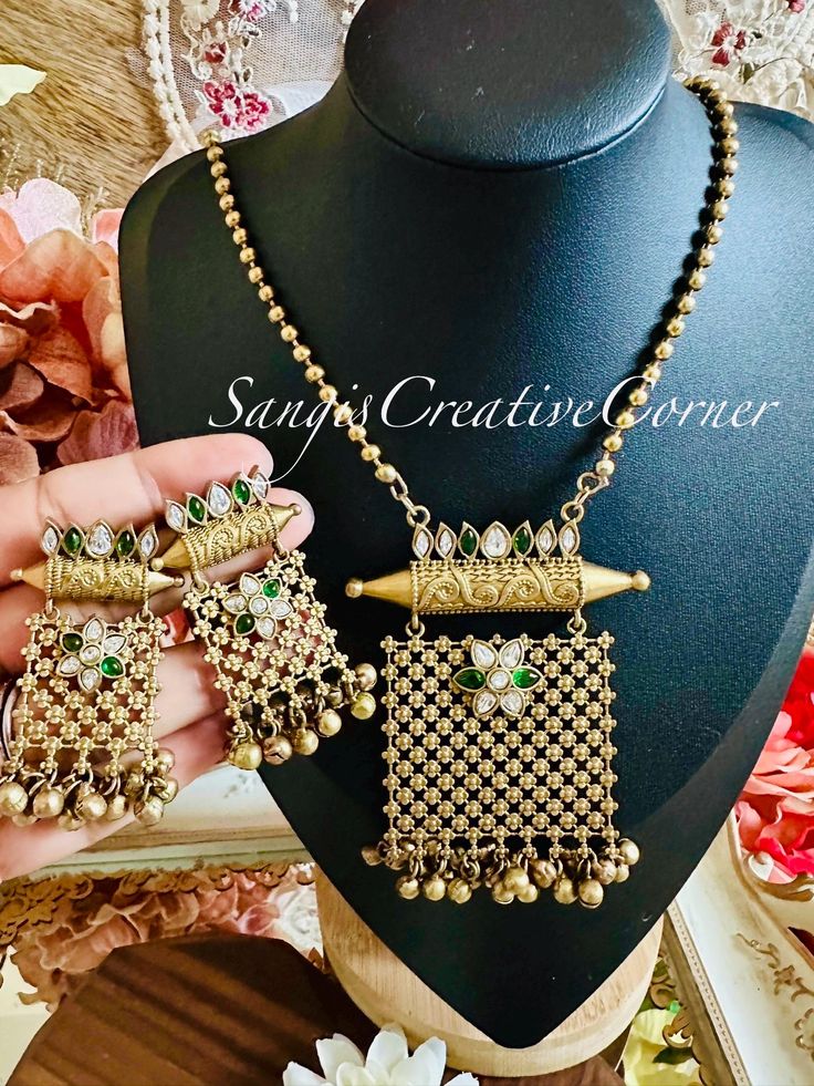 This brass-based textured antique gold/copper finish mala/ necklace style and earring set has a very gorgeous red/white or green/white (comes in 2 variations)  Kundan stones along with gunghoroo embellishments at the bottom of the necklace and earrings. throughout the piece. It has a brass-based metal finish with red-white Kundan stones as pictured. The combination of stone color with an antique gold/cooper brass-based metal finish make you look royal and regal. This finish is the right accent t Gold Temple Necklace With Antique Finish For Festive Occasions, Festive Gold Temple Necklace With Antique Finish, Brass Jewelry Sets With Intricate Design For Festive Occasions, Ornate Brass Kundan Necklace For Gift, Intricate Brass Jewelry Sets For Festive Occasions, Festive Brass Jewelry Sets With Intricate Design, Festive Gold Temple Necklace With Matching Earrings, Brass Jewelry Sets With Intricate Design For Celebrations, Gold Brass Temple Necklace With Antique Finish