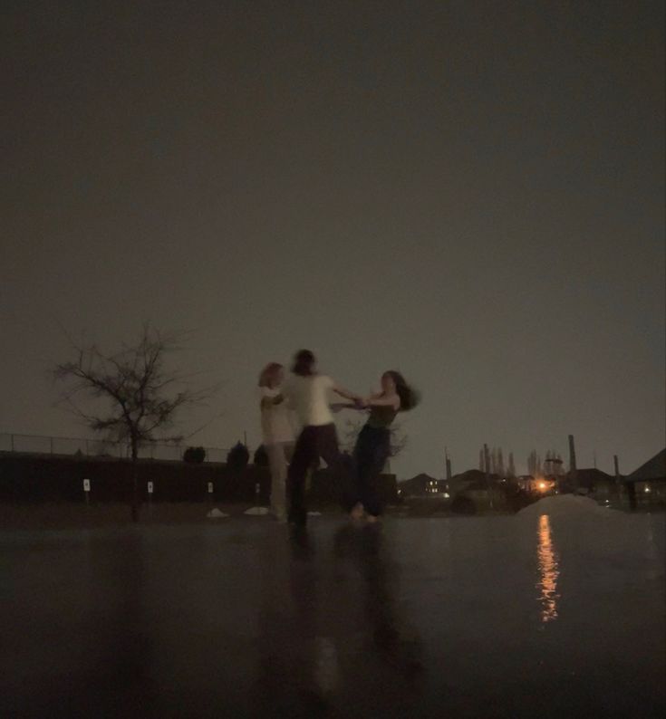 three people standing in the rain at night