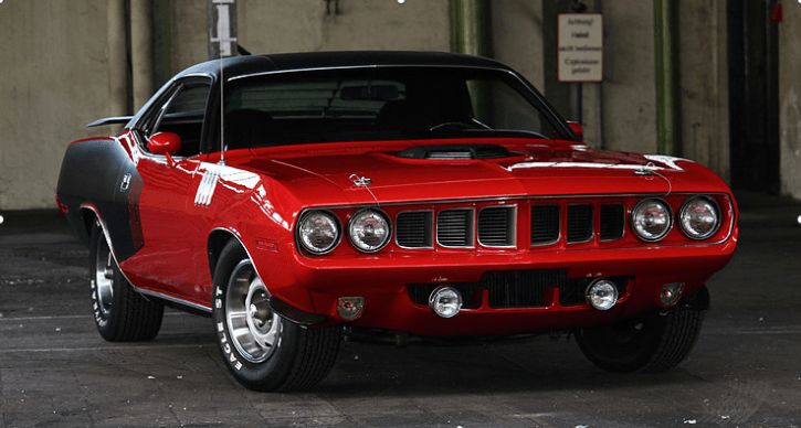 a red car parked in a parking lot next to a building with white lettering on it