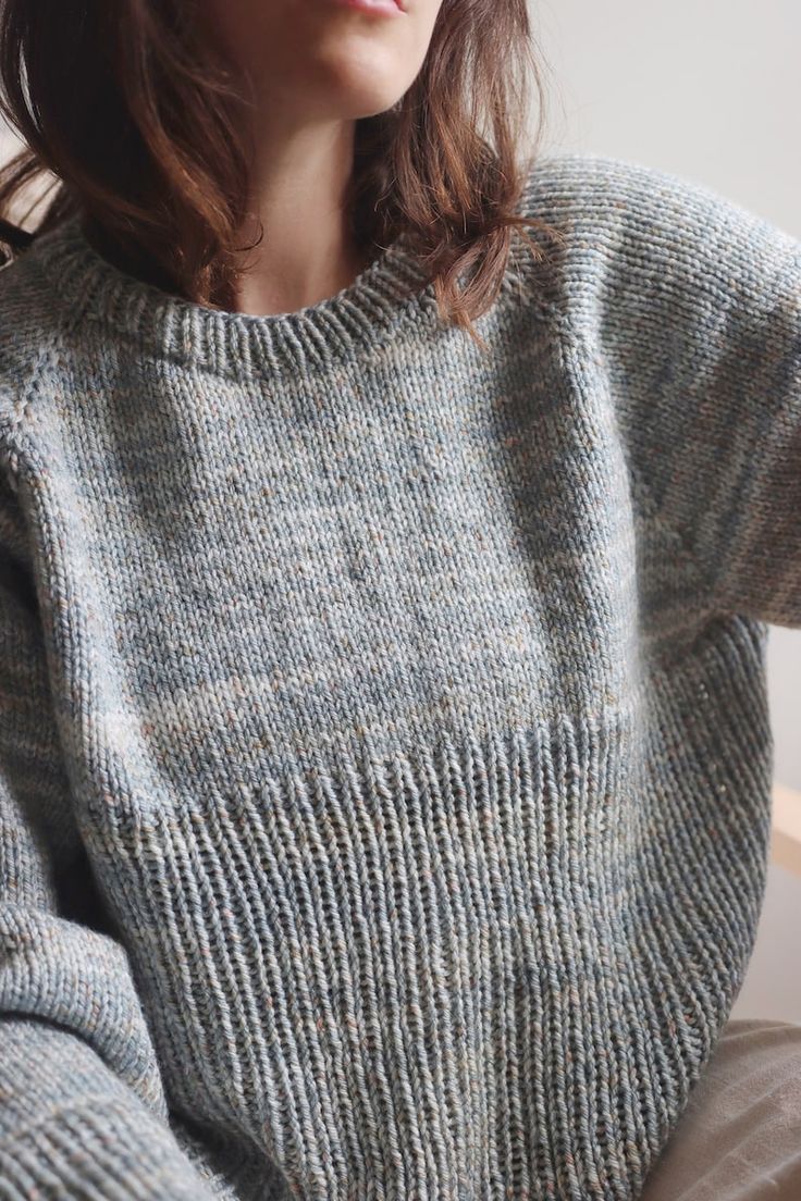 a woman wearing a gray sweater sitting down