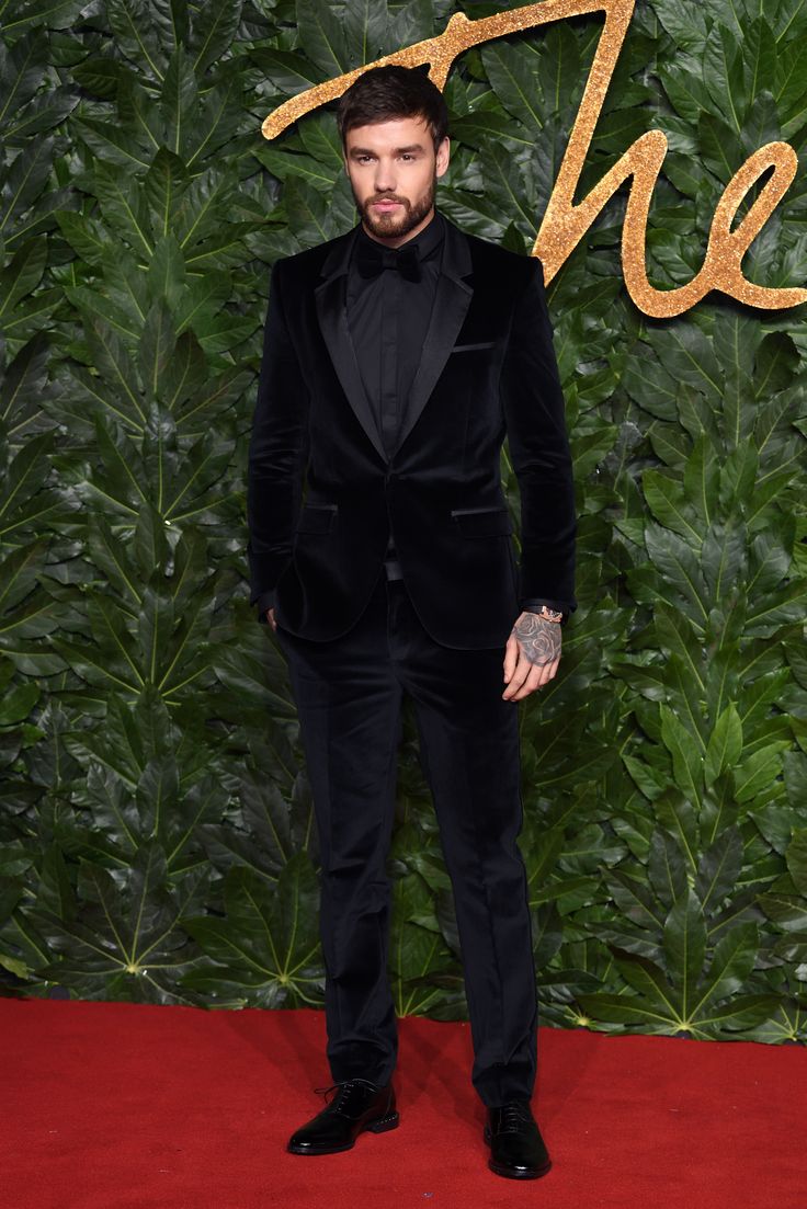 a man in a tuxedo standing on a red carpet