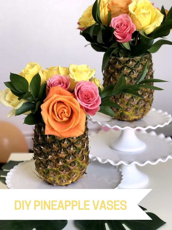 two pineapple vases filled with flowers on top of a white cake platter