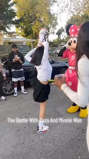 two people dressed as mickey and minnie dancing in the street