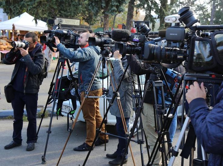 several people standing around with camera equipment on the side of the road in front of them