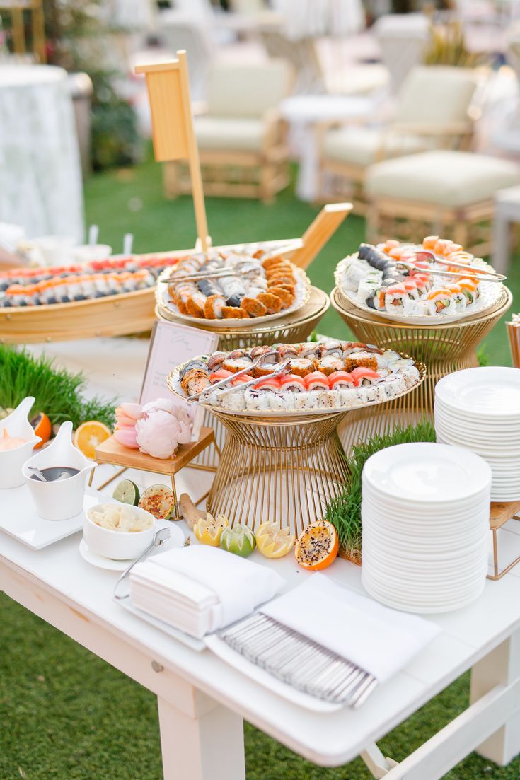 a table topped with lots of food on top of a lush green field