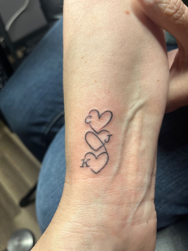 a woman's arm with two hearts and an arrow tattoo on the left wrist