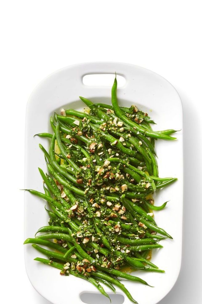 green beans with sesame seeds and seasoning on a white platter, top view