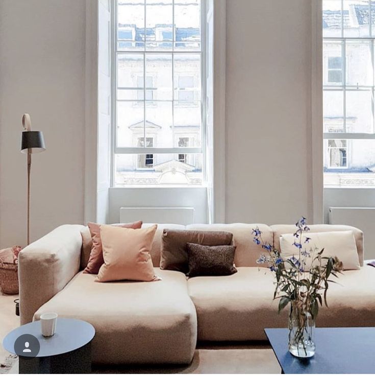 a living room filled with lots of furniture next to two large windows and a coffee table