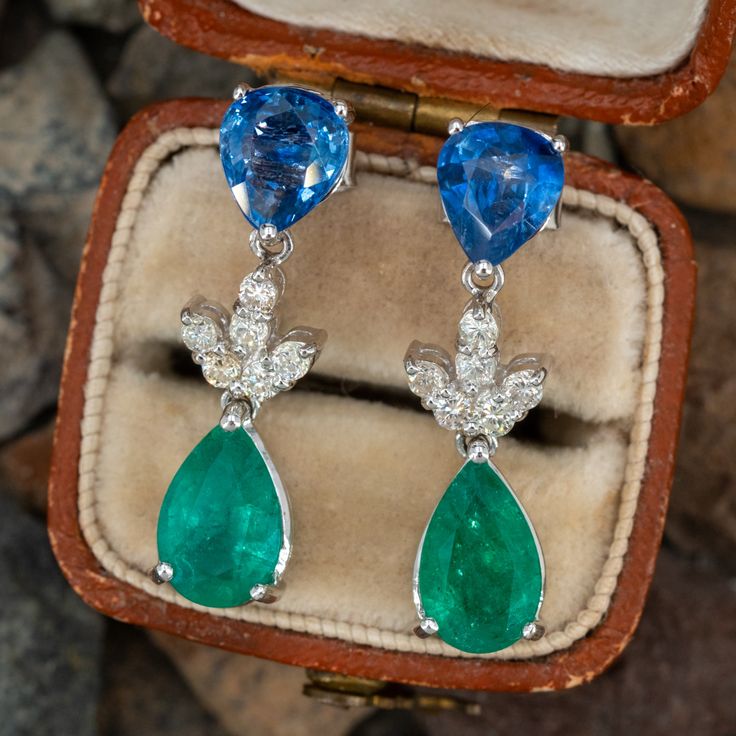 This fantastic pair of dangle earrings are each accented with one (1) pear mixed cut natural sapphire set into a three-prong setting, one (1) pear mixed cut natural emerald set into a three-prong setting and six (6) round brilliant cut diamonds set into a shared prong style setting. The earrings measure 26.0mm in length and 6.5mm wide. The earrings are finished with friction backs for pierced ears. Elegant Pear-shaped Gemstones For Formal Occasions, Fine Jewelry Pear-shaped Sapphire, Emerald Pear-shaped Fine Jewelry Earrings, Formal Pear-shaped Emerald Earrings, Fine Jewelry Pear-shaped Multi-stone, Fine Jewelry Emerald Pear-shaped Earrings, Pear-shaped Sapphire Jewelry With 17 Jewels, Elegant Multi-stone Drop Jewelry, Pear-shaped Emerald Earrings Fine Jewelry