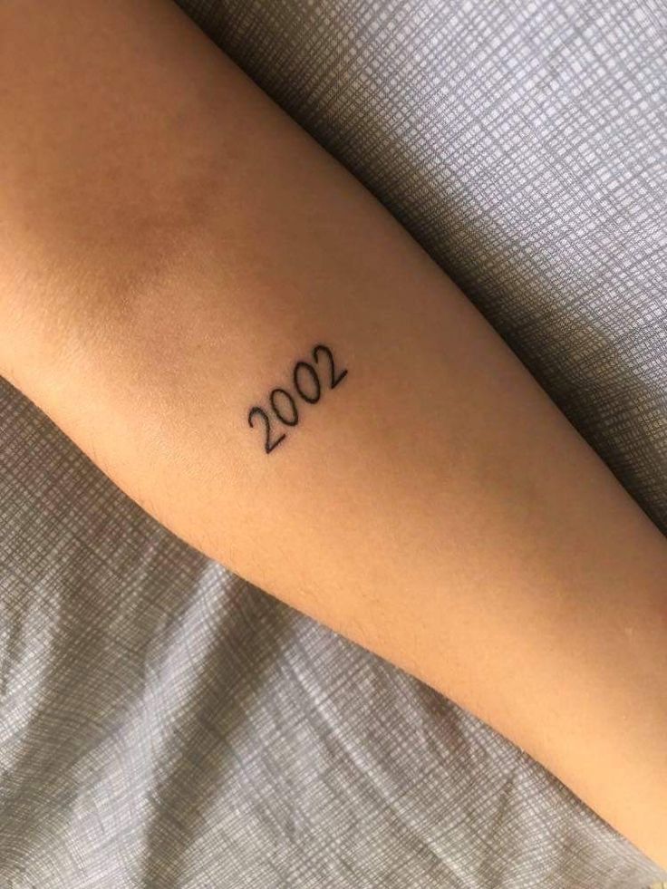 a person with a small tattoo on their arm that reads,'002 '