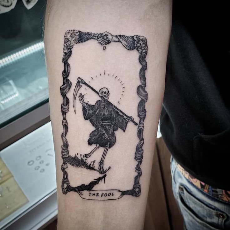 a person with a tattoo on their arm holding a sceptacle in the shape of a frame