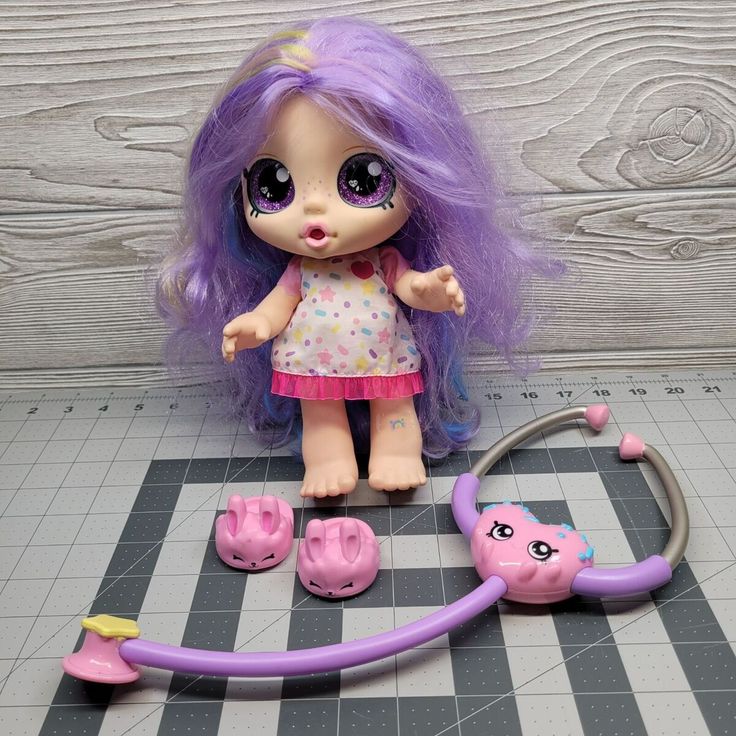 a doll with purple hair is next to a stethoscope on the floor