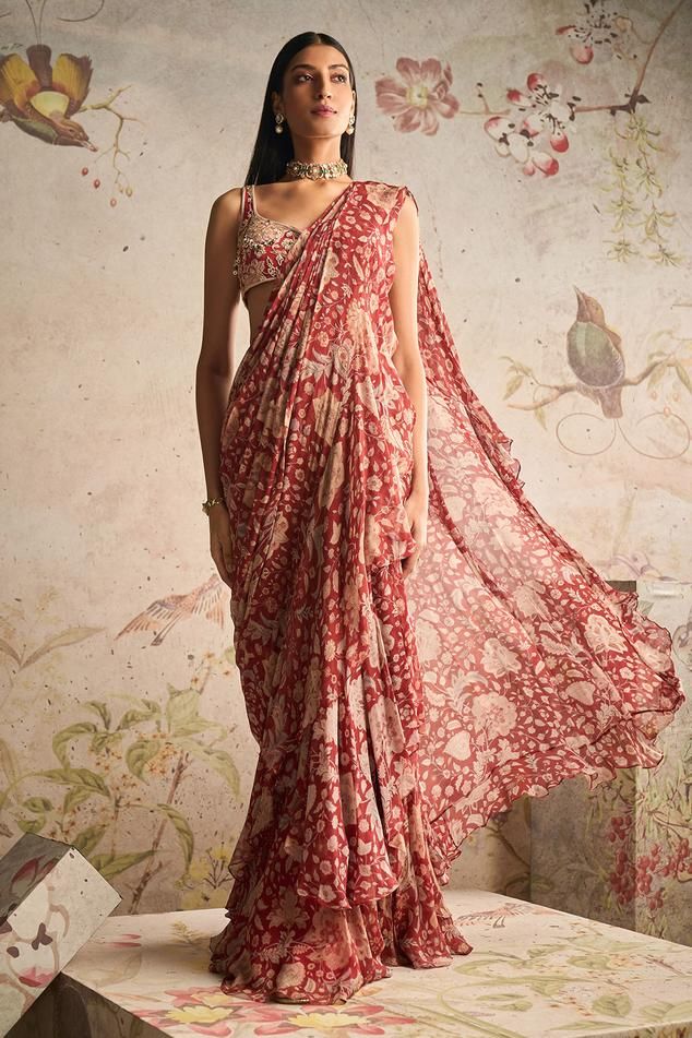 Red ochre pre-draped saree with all over floral print, pleated draped details, attached pallu and ruffle border. Paired with sweetheart neck printed blouse with all over 3D applique, beads, pearl, zari and sequin embroidery.
Components: 2
Pattern: Printed and Embroidered
Type Of Work: Floral Print, Pearl, Bead, Zari and Sequin Work
Neckline: Sweetheart Neck
Sleeve Type: Sleeveless
Fabric: Saree: Chiffon, Blouse: Net
Color: Red
Other Details: 
Beaded highlights
Occasion: Destination Wedding,Sange