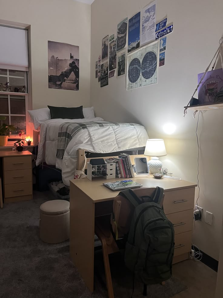 a dorm room with a bed, desk, and laptop on the computer table in front of it