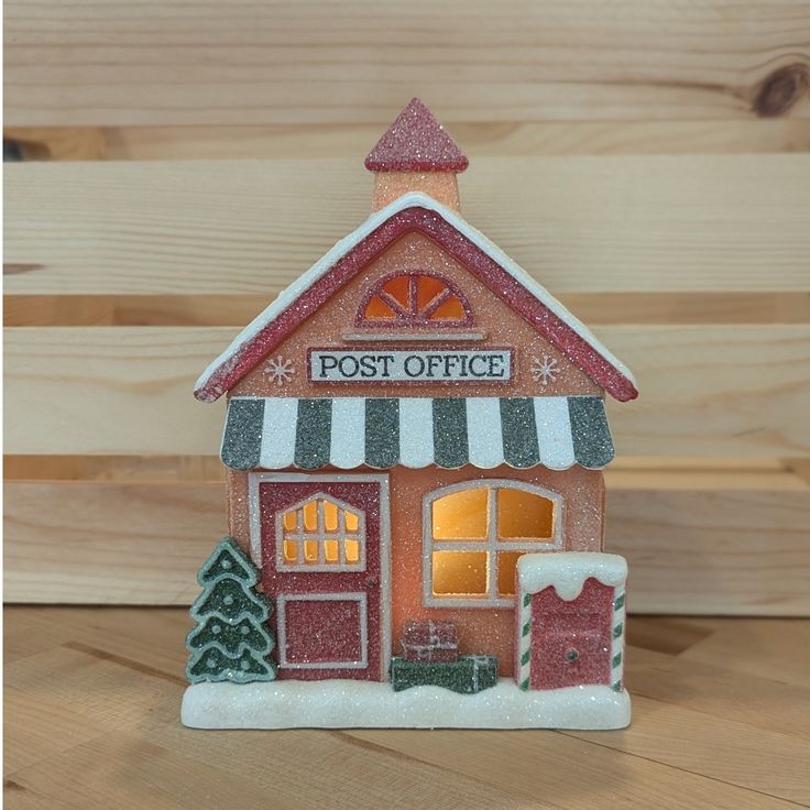 a small red and white post office with snow on the ground next to wooden planks