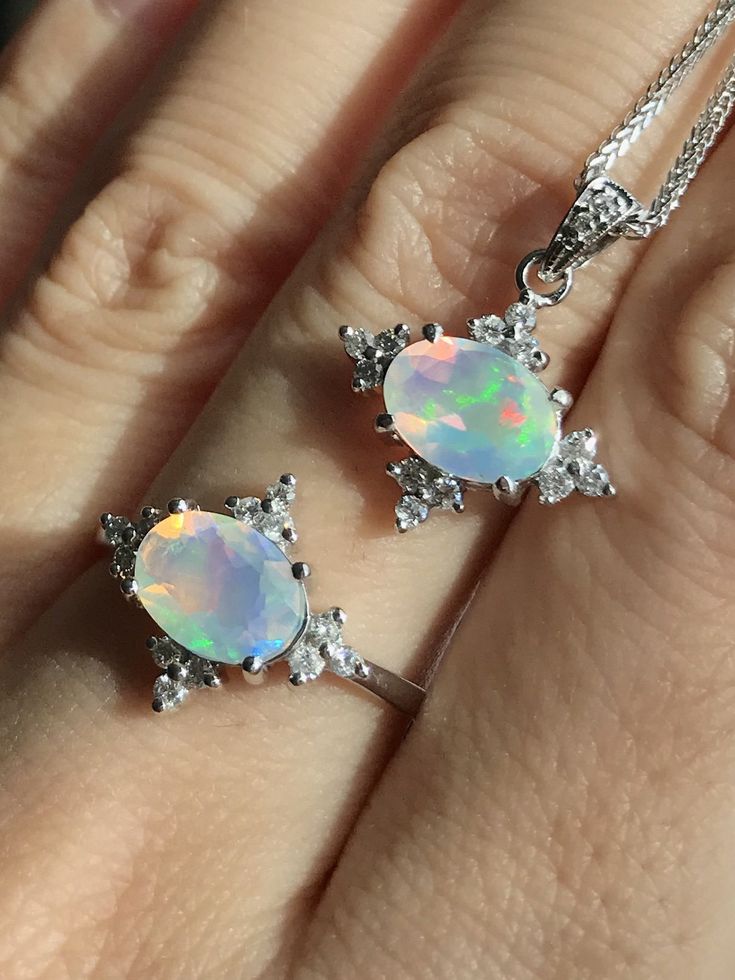 "A celestial inspired jewelry set featuring a a genuine, natural oval-sharped faceted Fire Opal accented with a halo of conflict-free white petite diamond handcrafted in 14k white gold. Wrapped in a Box ready to gift to your love one. Jewelry set features Ring with Matching Necklace Ring Info ----------------- 14k White Gold Opal measure 1.60tcw Diamond info: 0.28tcw F Color, VS clarity Ring Shank thickness 1.3mm HOW TO CARE FOR YOUR OPAL --------------------------------------------- Opals are s Oval Pendant Wedding Jewelry With Gemstone Accents, Oval Pendant Jewelry With Gemstone Accents For Wedding, Oval Pendant With Gemstone Accents For Wedding, Oval Pendant Jewelry With Accent Stones For Gift, Silver Celestial Jewelry With Oval Cabochon, Silver Celestial Oval Jewelry, Celestial Oval Gemstone Jewelry, Celestial Silver Oval Pendant Jewelry, Mystical Cabochon Jewelry For Anniversary