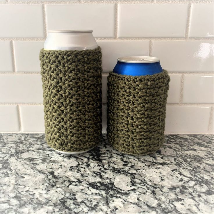 two crocheted can coolers sitting on top of a counter