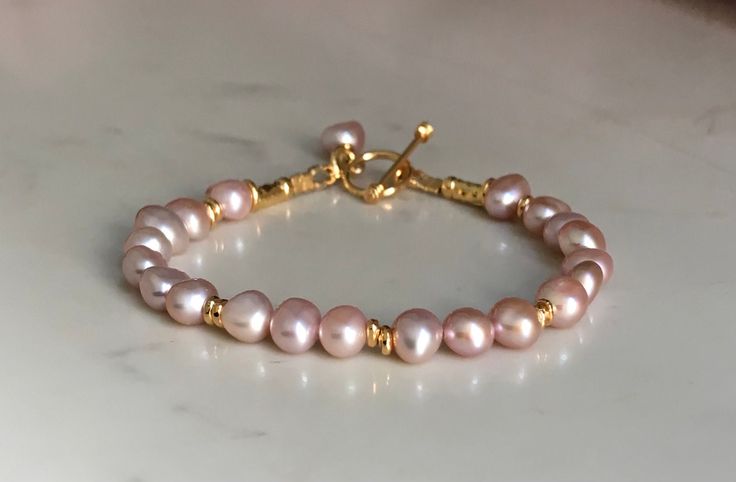 This listing is for one pink pearl bracelet only. There is matching necklace and earrings and another bracelet available on my website which are sold separately. Stunning bracelet of quality freshwater pearls with excellent lustre + Thai hill Tribe Silver 24kgold vermeil beads and toggle. Pearls measure 7mm x 6.5mm approximately. Thai hill tribe silver 24k gold vermeil (on silver)was used for all the beads and toggle. Length 19cms or 7.5 inches will fit wrist of 16.5cms or 6.5 inches High Luster Pink Jewelry For Anniversary, Gift Pearl Bracelet With High Luster Round Beads, Gift Pearl Bracelet With High Luster, High Luster Pearl Bracelet With Round Beads As Gift, High Luster Pearl Bracelet Gift, Elegant Pink Pearl Bracelet As A Gift, Elegant Pink Pearl Bracelet For Gifts, Elegant Pink Pearl Bracelet Gift, Elegant Pink Pearl Bracelet